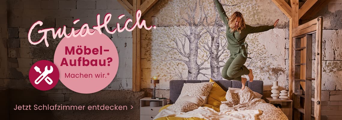 Möbel-Aufbau? Machen wir – Frau springt fröhlich auf Bett in gemütlichem Schlafzimmer, Text: Jetzt Schlafzimmer entdecken