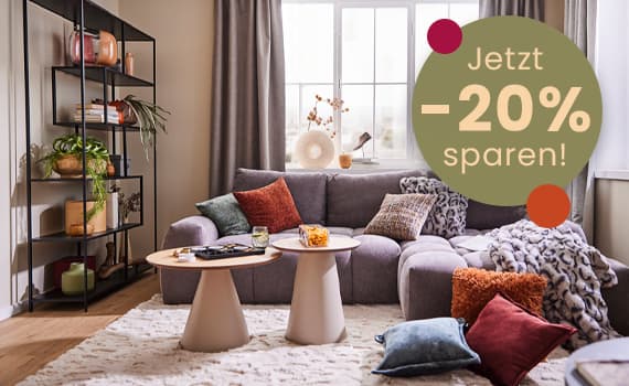 Jetzt -20% sparen! – gemütliches Wohnzimmer mit grauem Sofa, Couchtischen und bunten Kissen, Regal mit Pflanzen und Deko