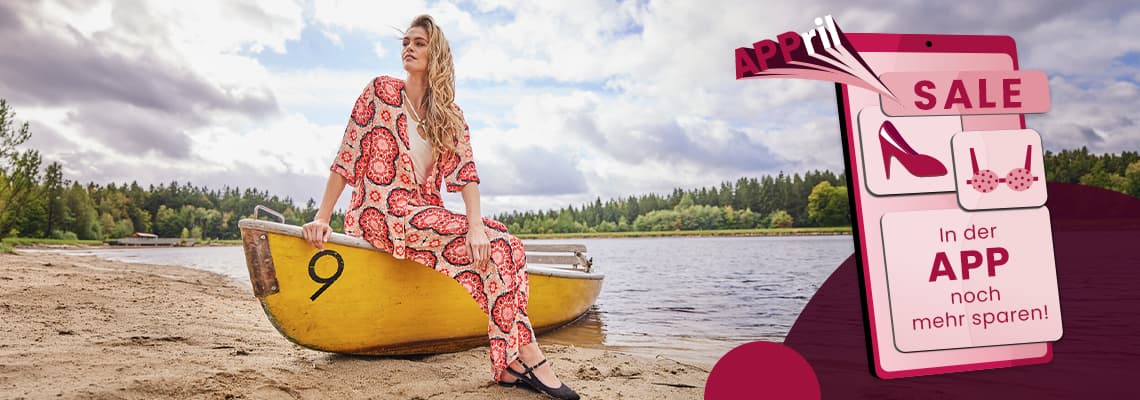 SALE – In der APP noch mehr sparen – Frau im gemusterten Anzug sitzt auf gelbem Boot am Seeufer